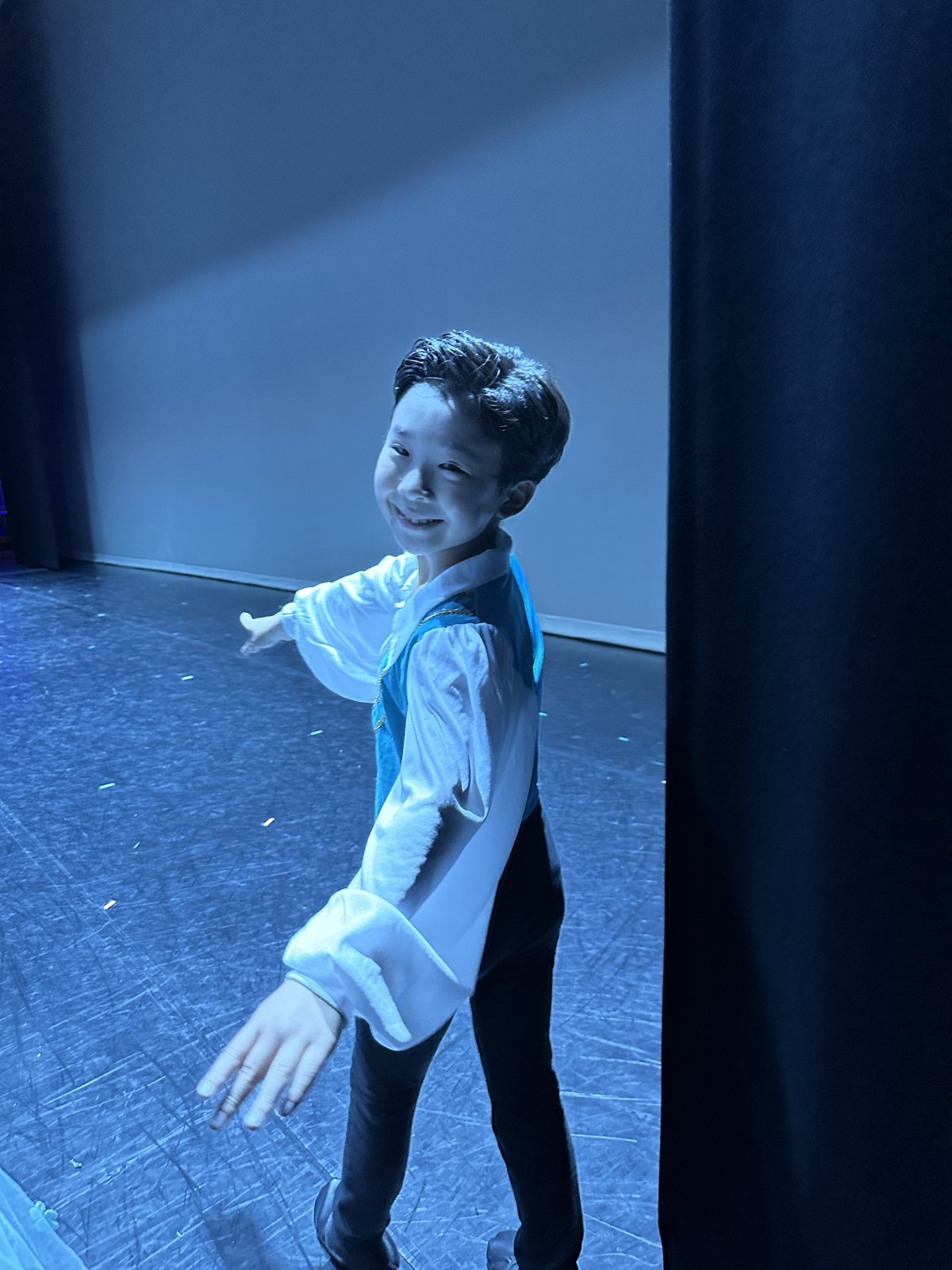 Jian in the stage wing in a blue vest costume